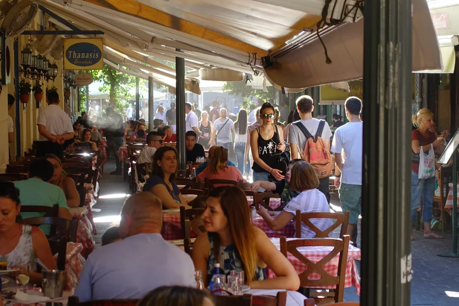 Diners and passersby beneath the awnings of a street-side cafe.