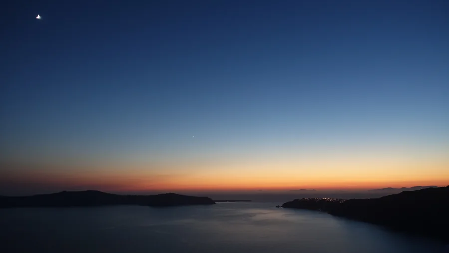 Dark island silhouettes beneath a sky fading from orange to deep blue.