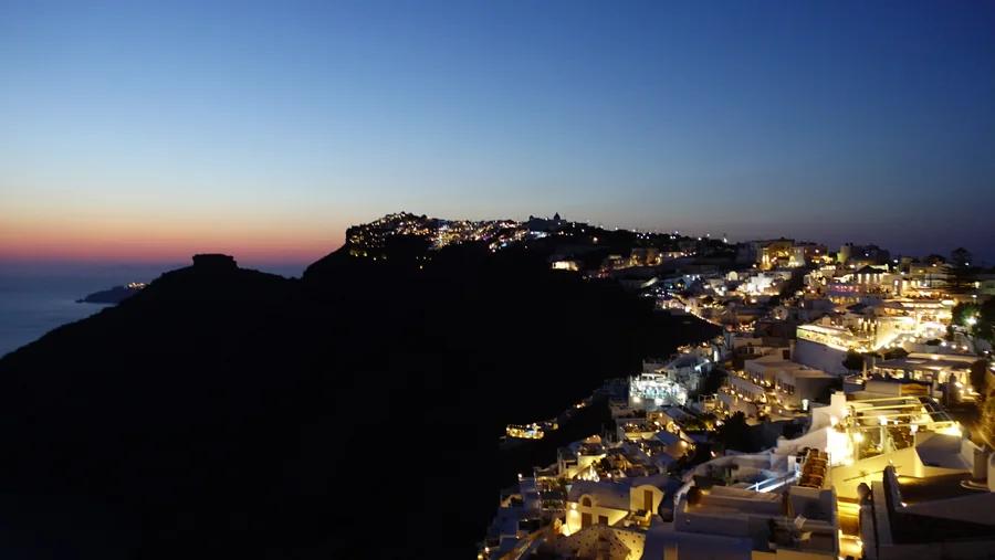 An illuminated coastal settlement against the evening sky.
