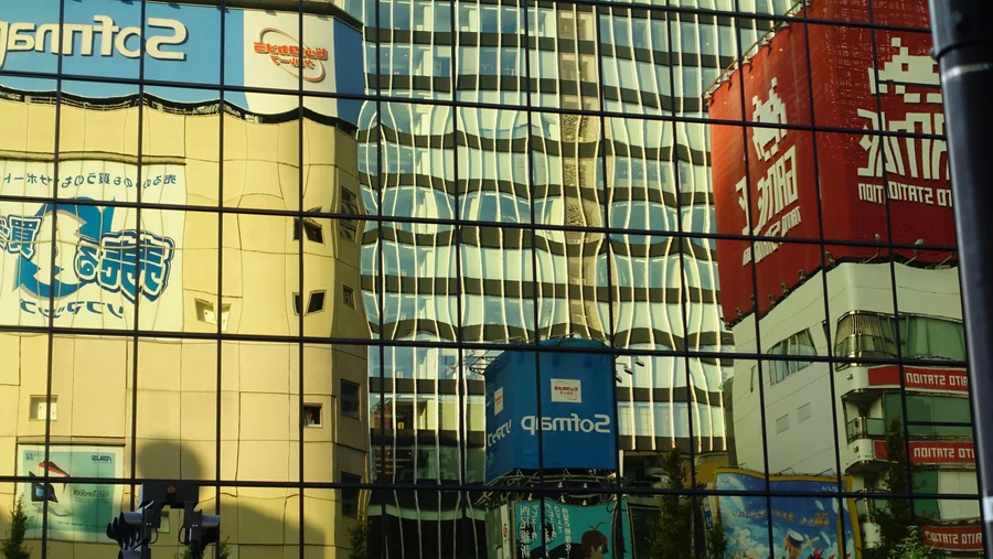 Buildings and signs reflected in a glass facade.